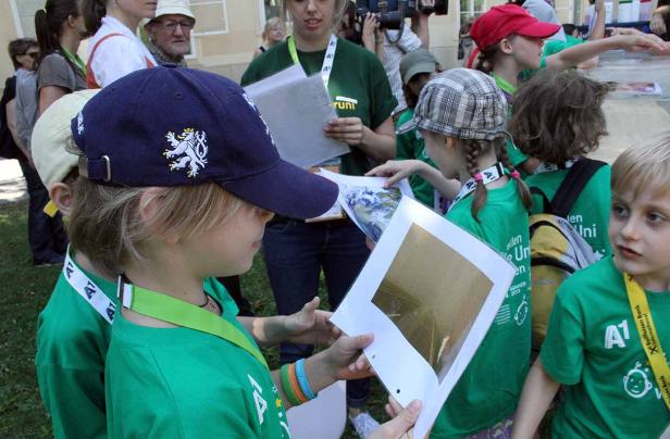 Eine Gruppe Kinder in grünen T-Shirts betrachtet Fotos und Dokumente.