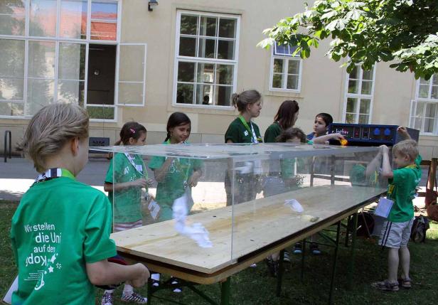 Kinder experimentieren mit einem Wasserbecken im Freien.