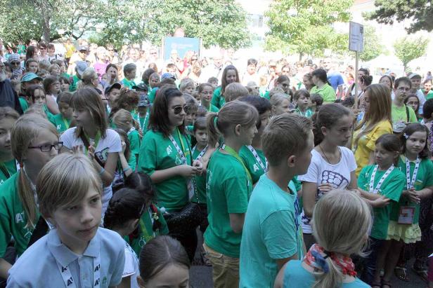 Eine große Gruppe von Kindern und Erwachsenen versammelt sich im Freien.