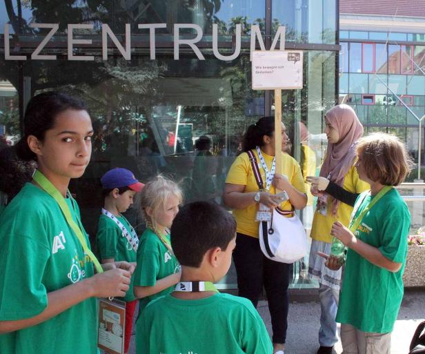 Eine Gruppe von Kindern und Erwachsenen steht vor einem Gebäude mit der Aufschrift „LZENTRUM“.