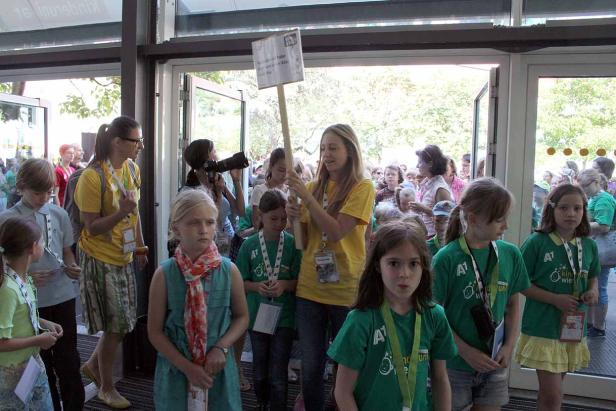 Eine Gruppe von Kindern und Erwachsenen steht vor einem Gebäude.