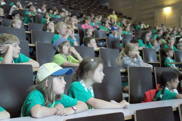 Viele Kinder sitzen in einem Hörsaal und hören aufmerksam zu.