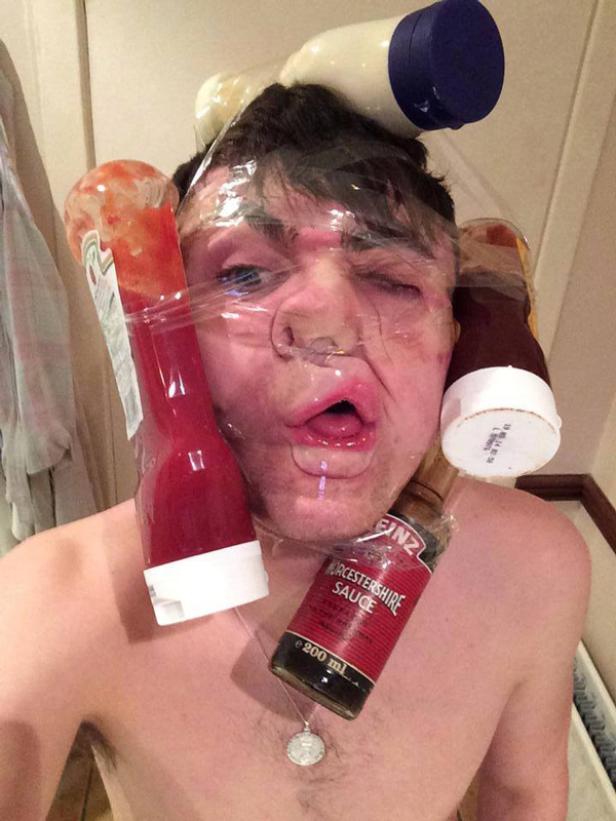 Ein Mann hat Saucenflaschen mit Frischhaltefolie an seinem Gesicht befestigt.