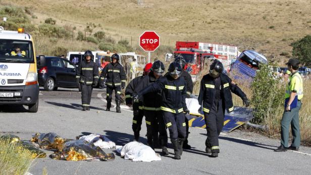 Nach einem Busunglück tragen Feuerwehrleute eine Bahre an Leichen vorbei.