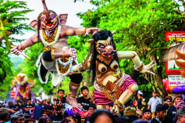 Zwei Ogoh-Ogoh-Figuren werden während einer Parade in Bali von einer Menschenmenge getragen.