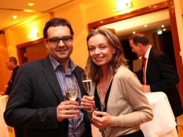 Ein Mann und eine Frau stoßen auf einer Party mit Sektgläsern an.