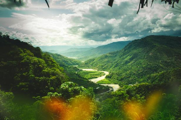 Ein gewundener Fluss schlängelt sich durch eine grüne Hügellandschaft in Peru.