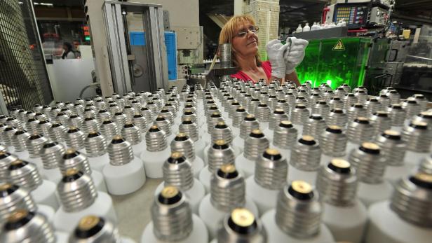 Eine Arbeiterin inspiziert Glühbirnen in einer Fabrik.