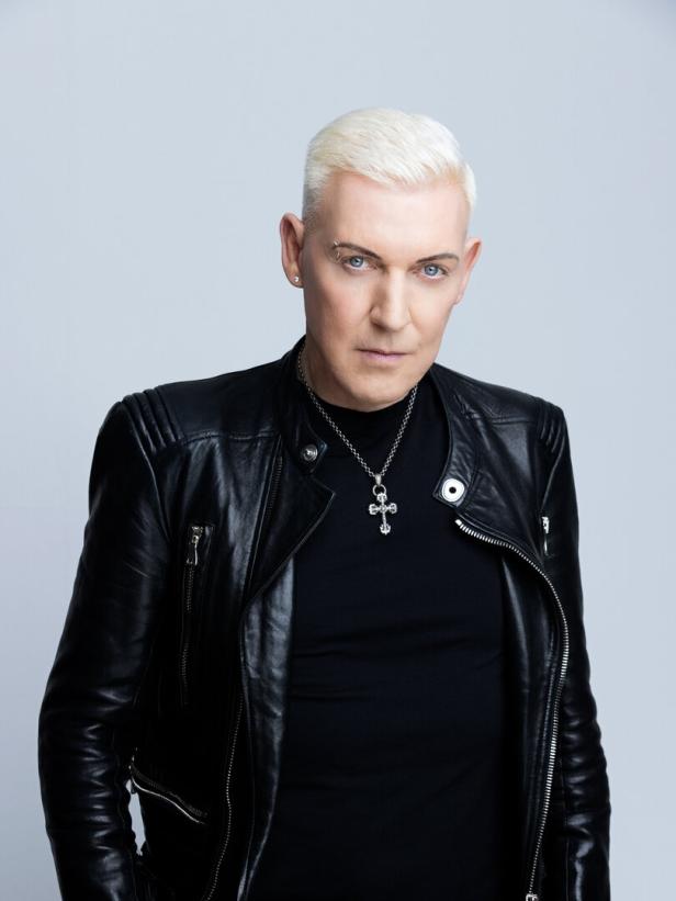 Ein Mann mit blonden, kurz geschnittenen Haaren und schwarzer Lederjacke blickt in die Kamera.