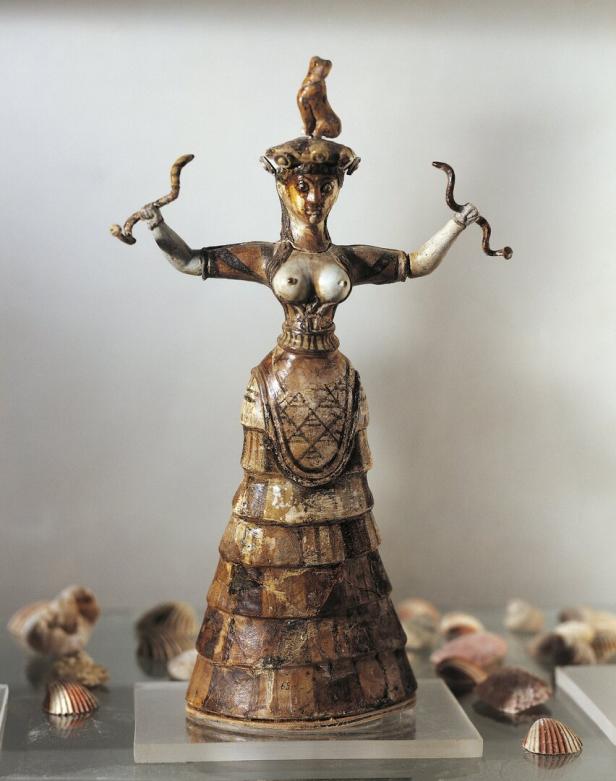 Eine minoische Schlangengöttin-Statuette mit erhobenen Armen und Schlangen in den Händen.