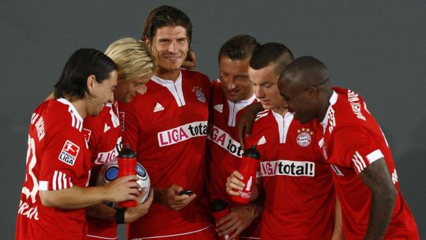 Eine Gruppe von Fußballspielern des FC Bayern München in roten Trikots steht zusammen.