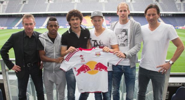Eine Gruppe von Männern posiert mit einem Red Bull Salzburg Trikot in einem Stadion.