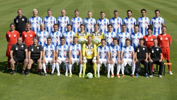 Ein Fußballteam posiert für ein Gruppenfoto auf einem grünen Rasen.