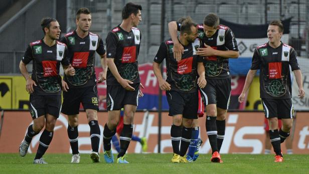 Eine Gruppe Fußballspieler in schwarzen Trikots steht auf dem Spielfeld.