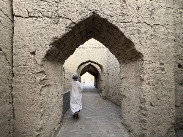 Ein Mann geht durch einen alten Torbogen in Nizwa.