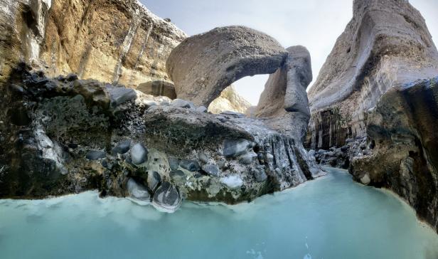 Ein Wadi mit einem natürlichen Felsbogen im Oman.