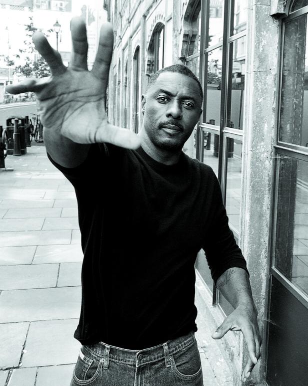 Idris Elba streckt seine Hand in Richtung Kamera.