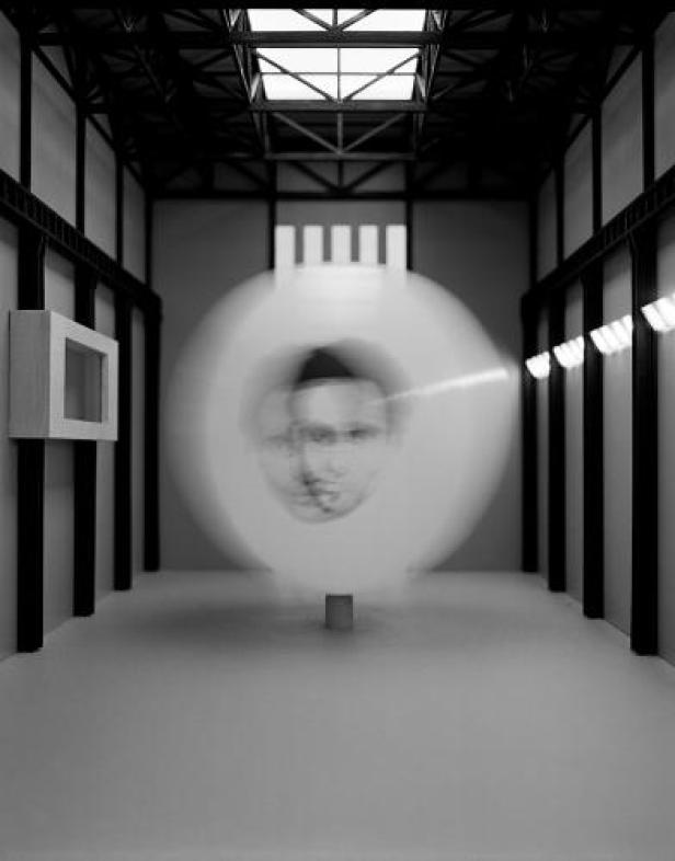 Eine Installation mit einem sich drehenden, verschwommenen Porträt in einem Ausstellungsraum.