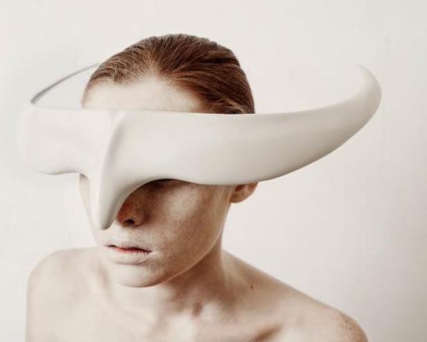 Eine Frau trägt eine skulpturale, weiße Maske, die ihre Augen bedeckt.