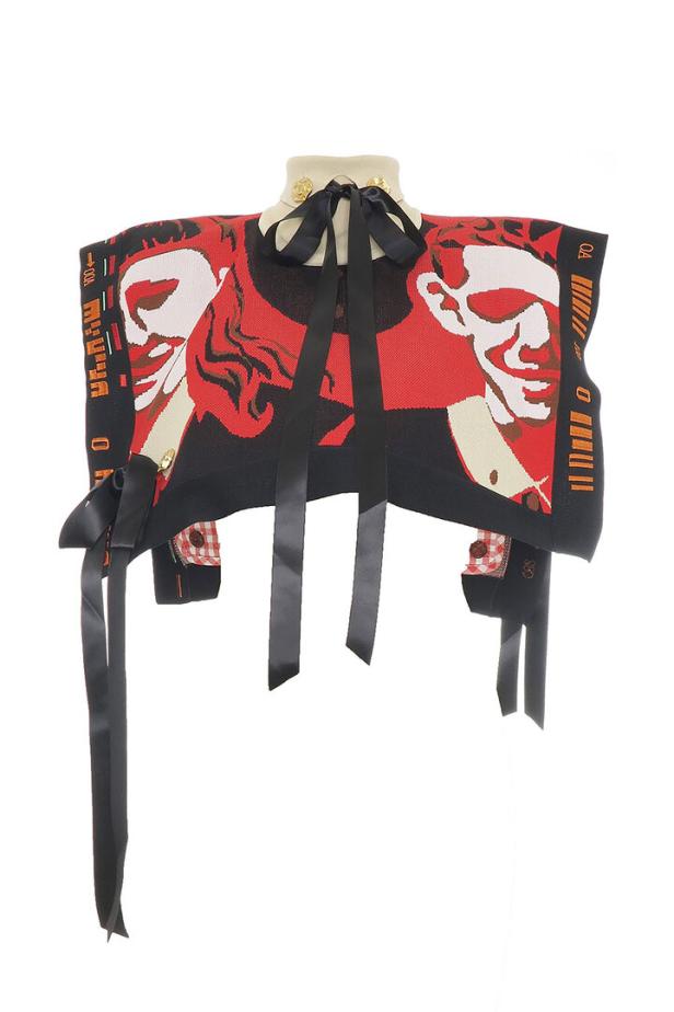 Ein ärmelloser Pullover mit einem roten Muster und schwarzen Schleifen vor einem weißen Hintergrund.