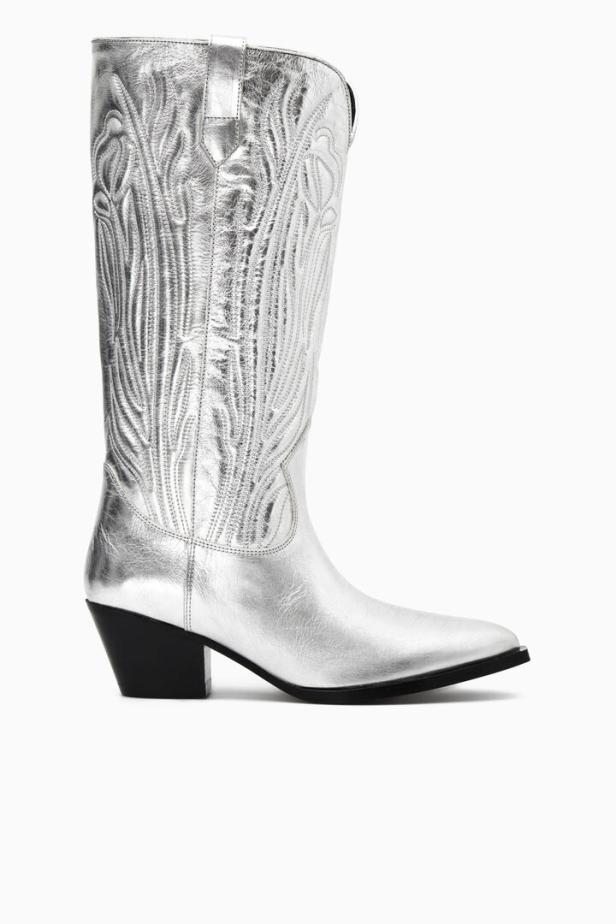 Ein silberner Cowboystiefel mit schwarzem Absatz steht vor einem weißen Hintergrund.