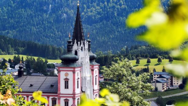 Die Kirche in Mariazell, umgeben von Bäumen und saftig grüner Landschaft.