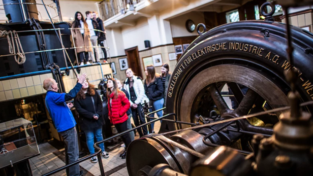 Eine Gruppe von Menschen besichtigt eine alte elektrische Maschine in einem Museum.