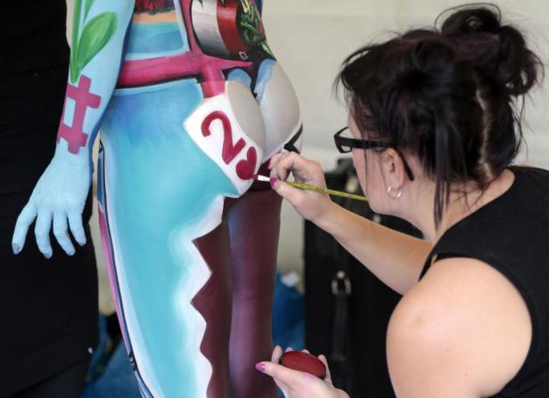 Eine Frau bemalt den Körper einer anderen Person mit verschiedenen Farben und Mustern.