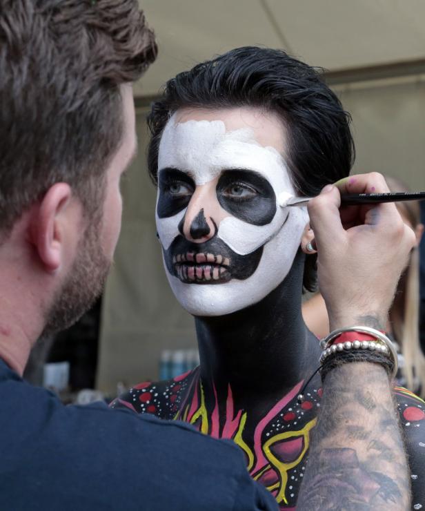 Ein Künstler schminkt eine Frau mit einem Totenkopf-Gesicht für Halloween.