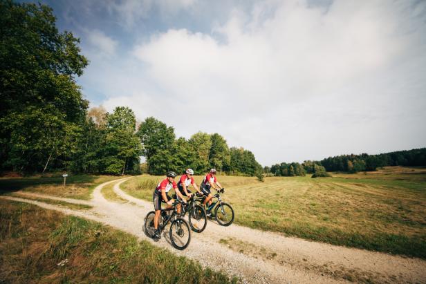 Drei Radfahrer fahren auf einem Schotterweg entlang des Iron Curtain Trail.