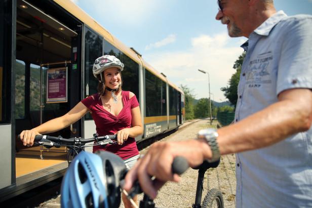 Eine Frau mit Fahrradhelm steht an der Wachaubahn und unterhält sich mit einem Mann.