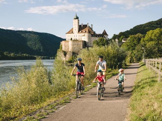 Eine Familie fährt auf dem Donauradweg in Schönbühel mit Fahrrädern.
