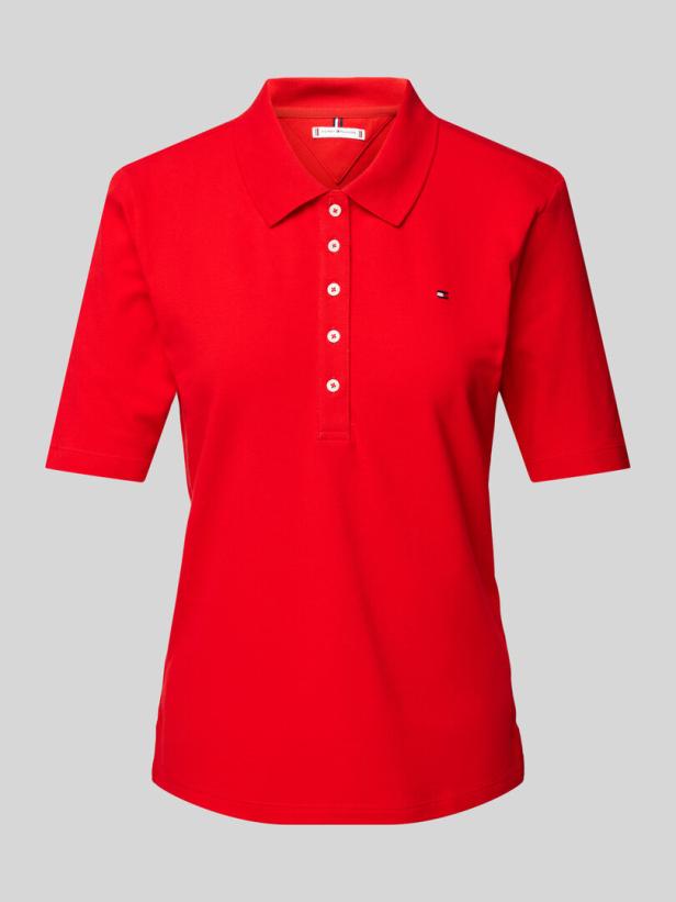 Ein rotes Poloshirt mit kurzen Ärmeln und weißen Knöpfen von Tommy Hilfiger.