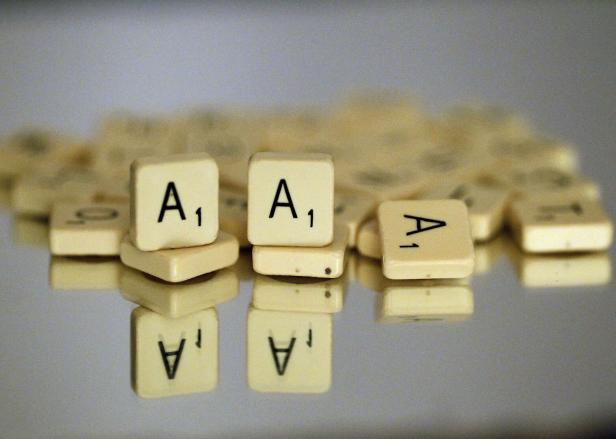 Mehrere Scrabble-Spielsteine mit dem Buchstaben A liegen auf einer spiegelnden Oberfläche.