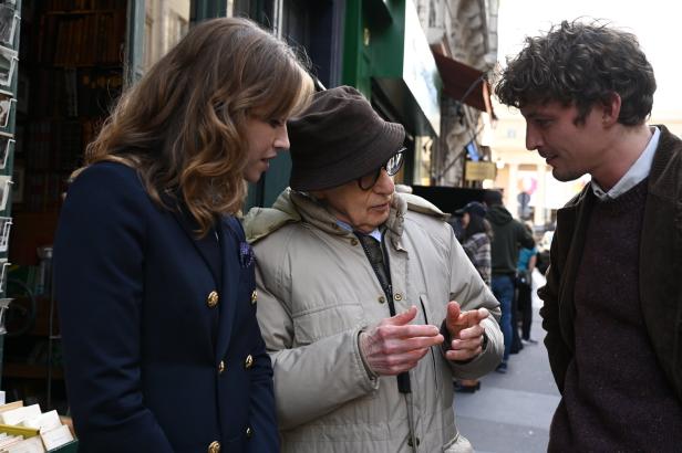 Woody Allen spricht mit zwei jungen Schauspielern auf einer Straße in Paris.