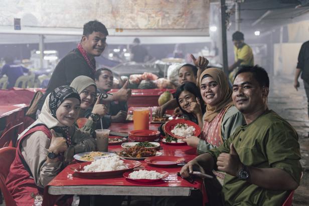 Menschen essen an einem Tisch in Kuching, Malaysia