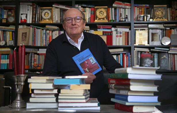 Ein Mann mit Brille hält das Buch „Lust auf Niederösterreich“ vor einem Bücherregal.