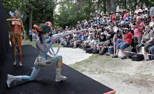 Zwei Frauen mit Körperbemalung posieren vor einer Gruppe von Fotografen.