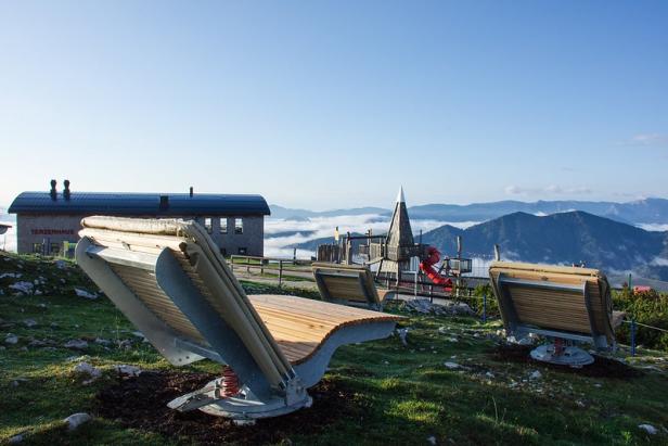 Blick von der Gemeindealpe Mitterbach auf eine Berglandschaft mit Spielplatz und Bänken.