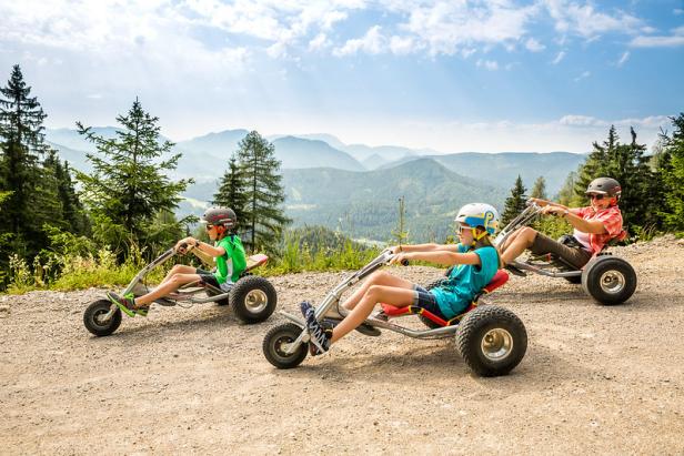 Kinder und eine Frau fahren mit Mountaincarts auf der Gemeindealpe Mitterbach.