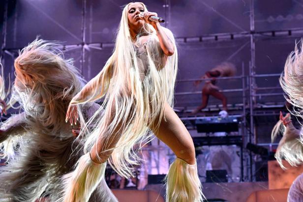 Doja Cat tritt mit Tänzern mit langen blonden Haaren auf einer Bühne auf.