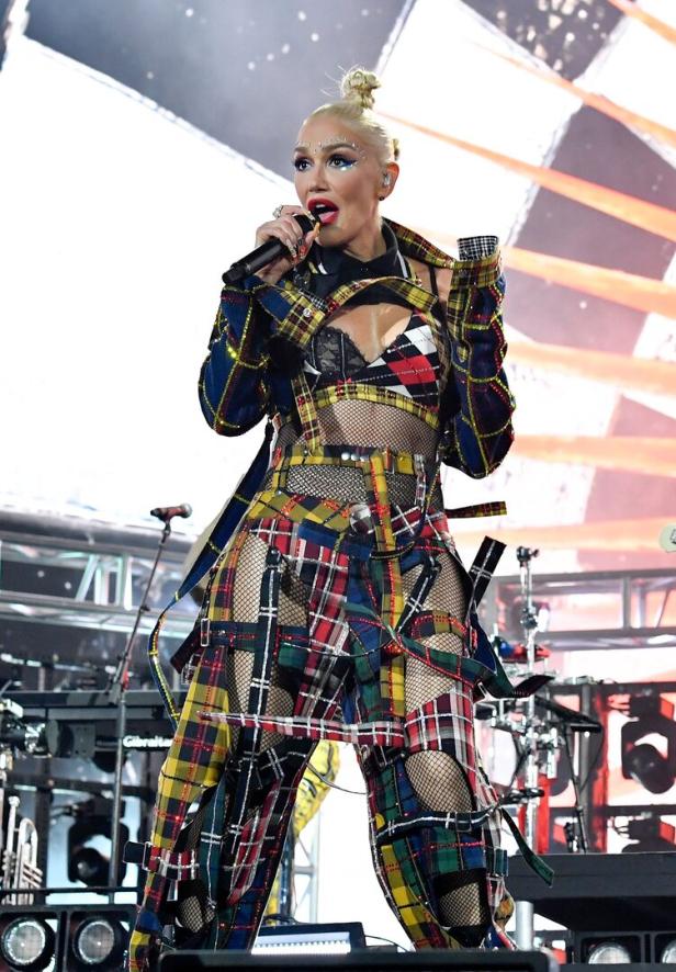 Gwen Stefani tritt in einem karierten Outfit mit Netzstoffdetails auf einer Bühne auf.