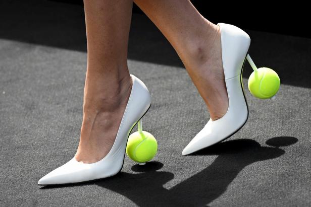 Nahaufnahme von weißen High Heels mit Tennisbällen als Absätze.