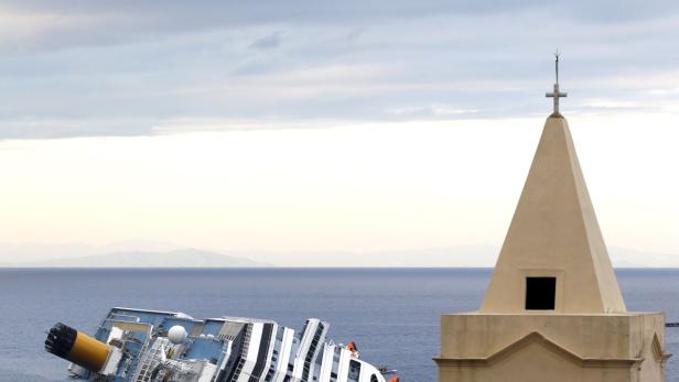 Die „Costa Concordia“ liegt gekentert vor der Küste, im Vordergrund ein Kirchturm.