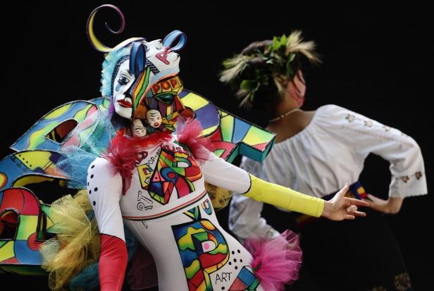 Eine Person in einem extravaganten Pop-Art-Kostüm steht neben einer Tänzerin.