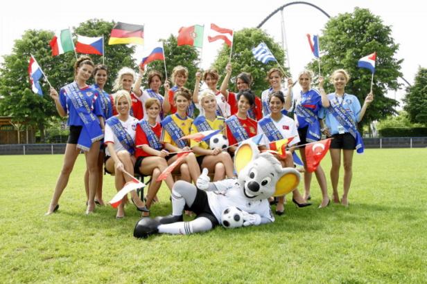 Mädchen in Trikots verschiedener Nationalmannschaften posieren mit Flaggen und dem Maskottchen des Europa-Parks.