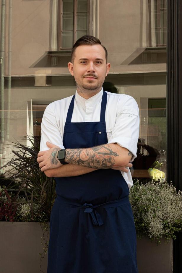 Der Küchenchef des Gasthaus Artner auf der Wieden steht in Kochschürze vor seinem Lokal in Wien-Wieden.