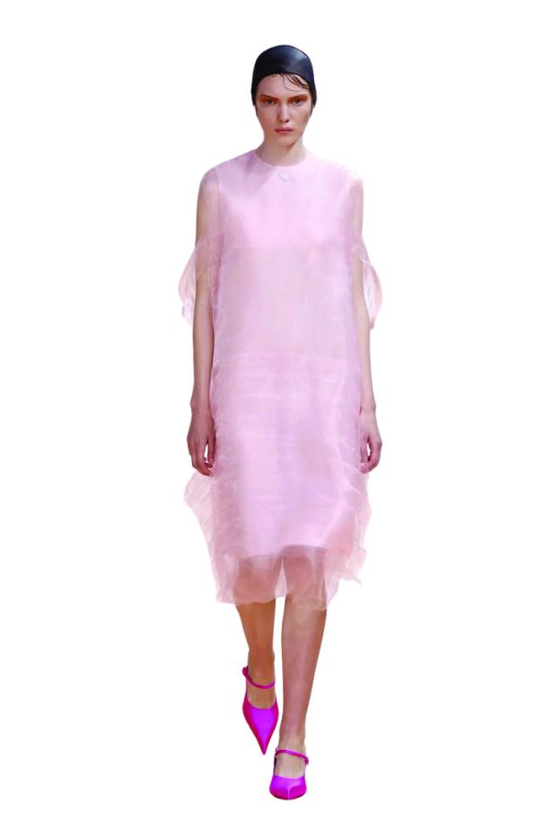 Ein Model in einem transparenten, rosa Kleid und pinkfarbenen Schuhen auf dem Laufsteg.