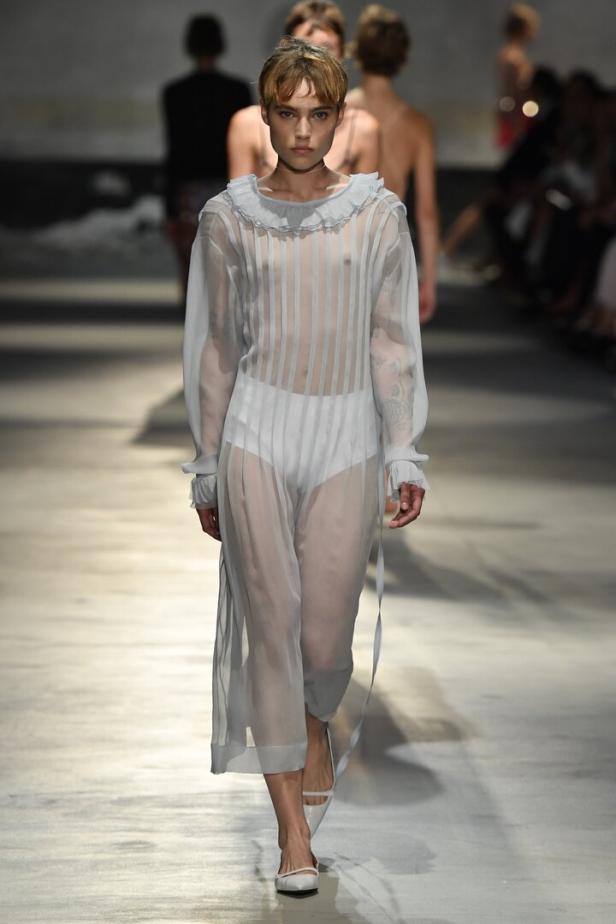 Ein Model läuft in einem transparenten, hellblauen Kleid über einen Laufsteg.