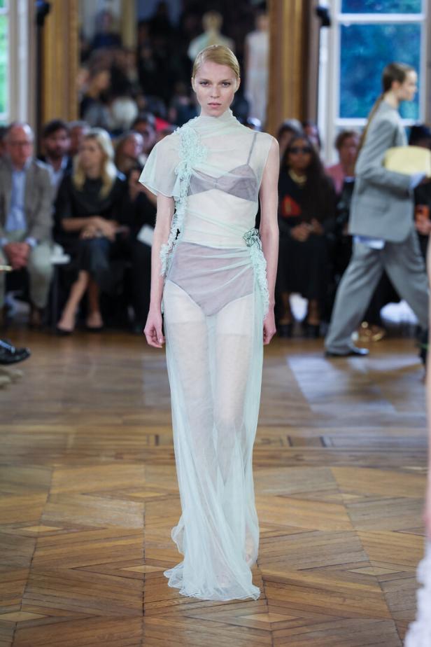 Eine Frau in einem transparenten, hellgrünen Kleid auf einem Laufsteg.